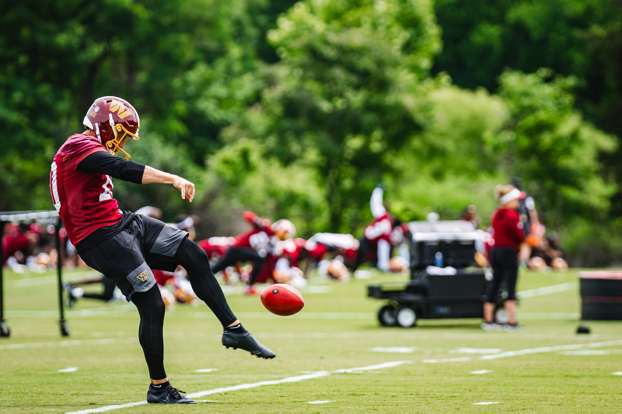 Washington Commanders punter boots a punt during OTA Session 3